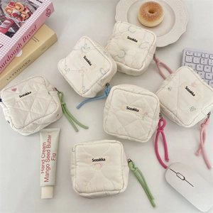 Quilted mini pouches with colorful zipper pulls and heart patterns in a lifestyle setting