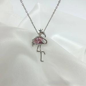 Detail shot of flamingo pendant with pink pear-cut zircon on white silk background