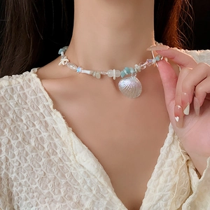 Detail of beaded beach necklace featuring a lustrous shell pendant on a model neck