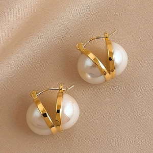Macro shot of minimalist gold plated hoop earrings featuring elegant white pearls