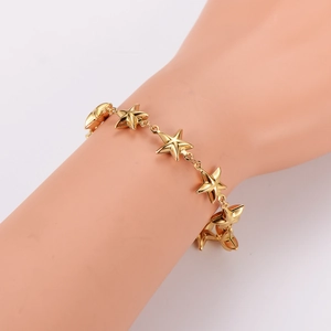 Vintage 18K gold star charm bracelet shown on wrist with metal link chain and secure clasp