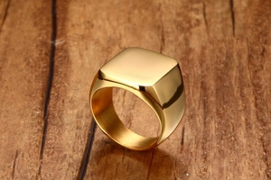 Polished gold square signet ring for men displayed on a warm textured wooden surface