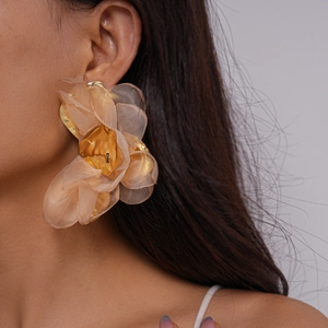 Gros plan de boucles d'oreilles fleurs en mousseline beige portées par un mannequin