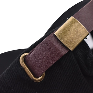 Detail of adjustable reddish-brown leather strap and bronze buckle on black cotton cap