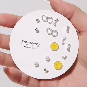 Detail view of a 7-pair silver stud earring set with hearts, stars and yellow smileys