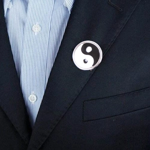 Close-up of Tai Chi Yin Yang enamel lapel pin on a dark blue suit jacket collar