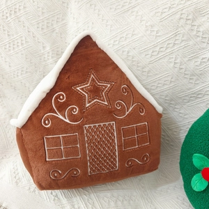 Macro shot of gingerbread house plush toy with white embroidery details on soft fabric