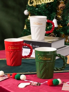 Close-up of knit texture ceramic Christmas mugs with golden Merry Christmas text and handles