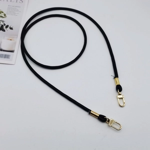 Close-up of black PU leather shoulder strap with gold spring clasps on white background