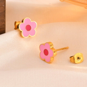 Macro detail of pink flower stud earring with gold edges on white silk background