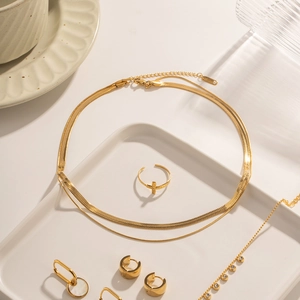 Vue à plat de chaînes Miami Cuban et serpent dorées 18K avec bagues croix et boucles d'oreilles
