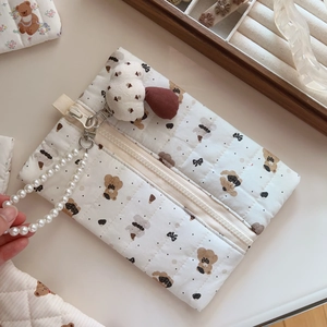 Detailed view of quilted bear pattern bag with pearl handle and plush mushroom charm