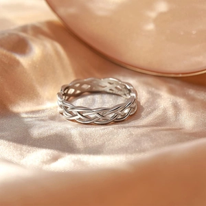 Close-up of S925 sterling silver woven ring on elegant light gold silk background