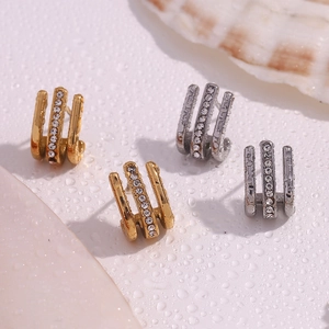 Macro view of gold and silver triple-row J-shaped earrings with sparkling rhinestones
