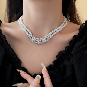 Close-up of double-layer pearl necklace with sparkling rhinestone flower on a model