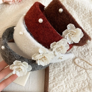 Close-up of plush velvet floral headbands with faux pearls in multiple autumn colors