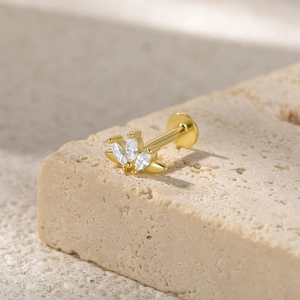 Macro shot of gold S925 silver ear stud with marquise crystals on a stone texture