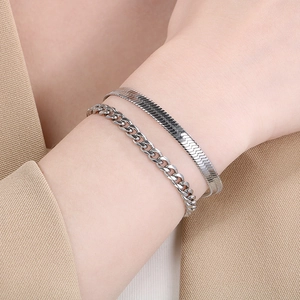 Close-up of double layered silver snake and cuban chain bracelets on wrist with suit