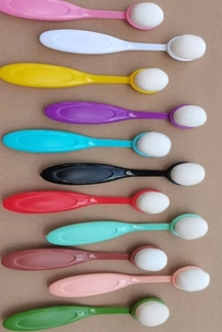 Flat lay showing multiple colorful flexible toothbrush-style foundation brushes in various shades