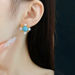 Close-up of vintage turquoise stud earring with pearls and gold hollow frame on ear