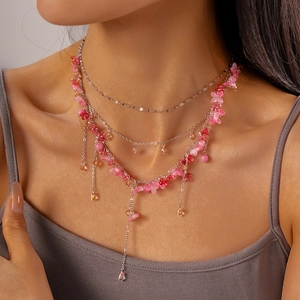 Close-up of triple-layered necklace with pink resin flowers and beaded tassel details