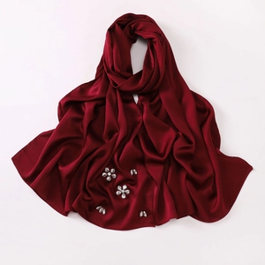 Detail of burgundy satin silk hijab featuring handcrafted rhinestone floral patterns