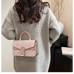 Détail d'un sac rose clair en dentelle avec broderies papillons 3D et anse tressée