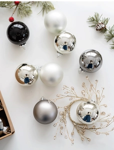 Close-up of 6cm Christmas glass balls in pearl white, silver, and black on festive pine