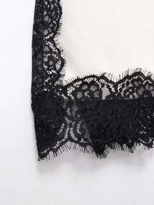 Macro detail of intricate black eyelash lace stitched onto white satin camisole top