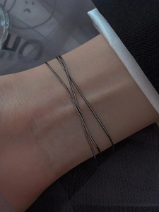 Close-up of minimalist double-layered black crisscross bracelet on female wrist