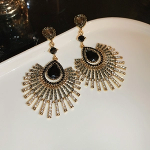 Vue détaillée de boucles d'oreilles dorées vintage avec gemmes noires et strass gris