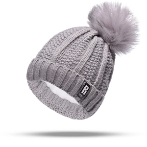 Detailed view of grey knitted beanie with thick faux fur lining and large pompom