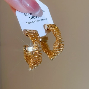 Macro shot of twisted gold-plated hoop earrings with intricate metallic wire textures