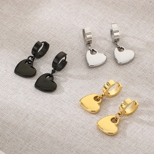 Detailed flat lay of heart charm earrings in black, gold and silver stainless steel