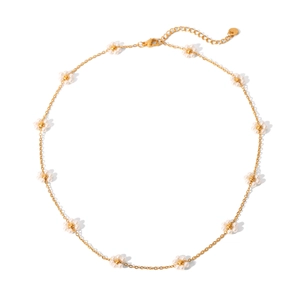 Dettaglio della collana dorata con fiori di perle e chiusura a moschettone su sfondo bianco