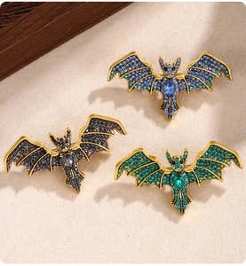 Detail of bat brooches with colorful rhinestones in blue green and purple on gold alloy