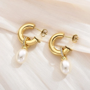 Détail de boucles d'oreilles dorées en C avec pendentifs perles et oxydes de zirconium