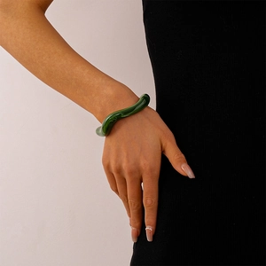 Close-up of deep green wavy acrylic bangle with translucent resin texture on wrist