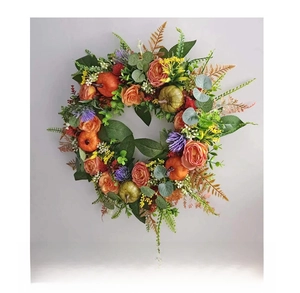 Side view detail of an autumn harvest wreath with orange roses and mini pumpkins