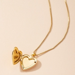 Vintage gold heart locket necklace with open pendant design on a beige background