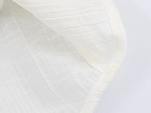 Detail shot of white textured fabric showing fine stitching and semi-transparent weave