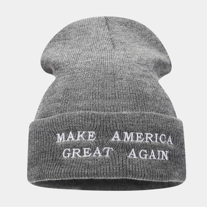 Close-up detail of white embroidered text on a gray knit beanie with ribbed texture