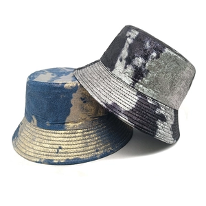 Two reversible tie-dye bucket hats in blue-gold and black-gray metallic textures
