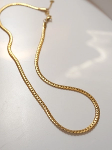 Detail of gold flat snake bone chain with lobster clasp and adjustable extension link