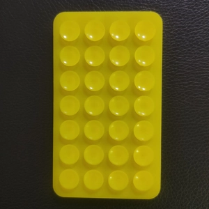 Close-up of a bright yellow 28-suction cup silicone phone mat on black background