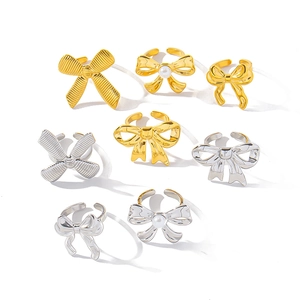 Eight bow tie 18K gold and silver plated stainless steel rings set on white background