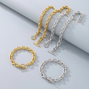 Flat lay of gold and silver stainless steel OT buckle chain bracelets on grey background