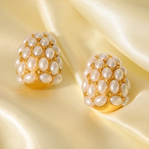Vintage gold teardrop earrings with inlaid white pearls on elegant silk fabric background
