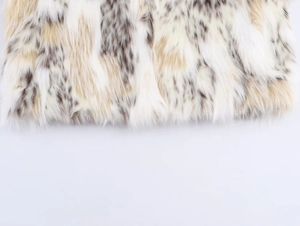 Macro shot of faux fur texture with beige and dark brown leopard spots on soft white fabric