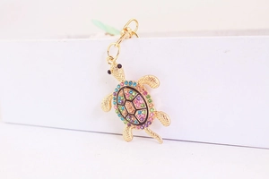 Dettaglio laterale di un portachiavi tartaruga placcato oro con strass multicolore